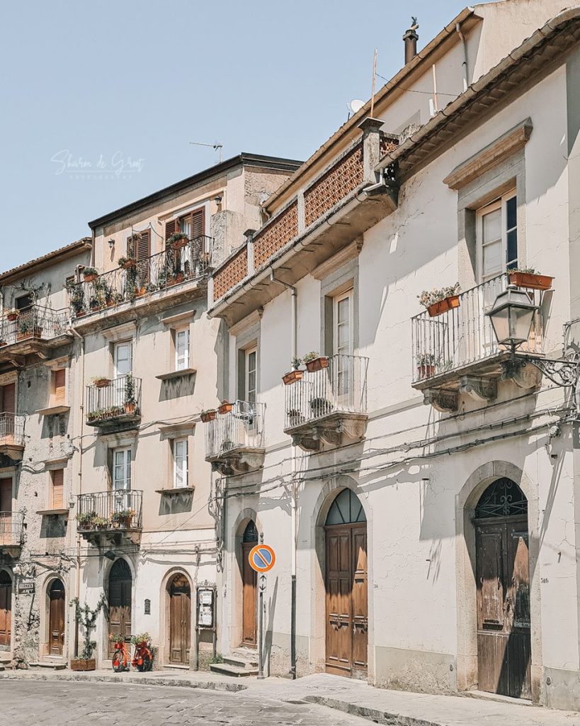 Street in Novara di Sicilia with balconies and plant potters. 